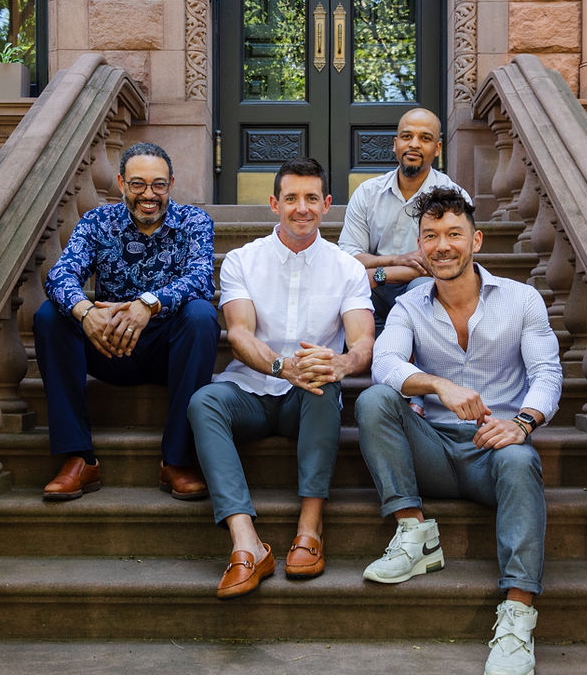 Harlem Properties Team seated on a Harlem brownstone stoop